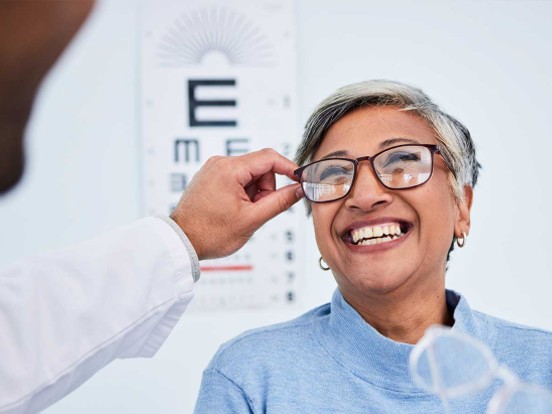 Smiling lady trying on glasses at the opticians