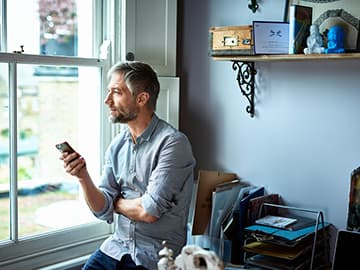 Man on speaker call at home looking out the window
