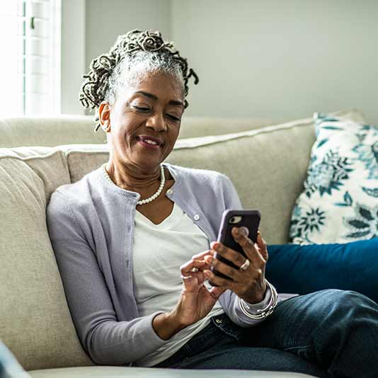 Lady with dreads using mobile phone on sofa