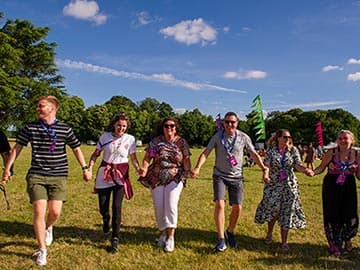 Simplyhealth colleagues holding hands in a line in a field