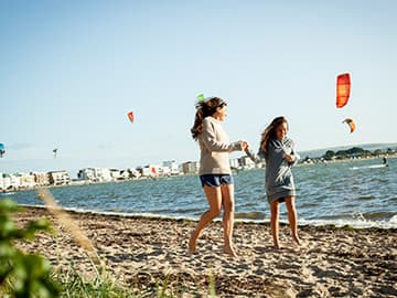 Mother and daughter walking along a sandy beach