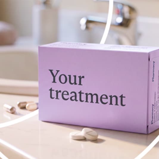A lavender box labeled "Your treatment" on a bathroom counter with scattered pills in front and a blurred faucet in the background.