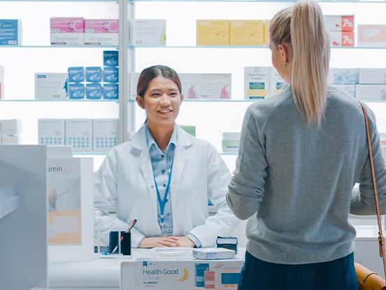Woman collecting prescription from a pharmacy worker at a counter