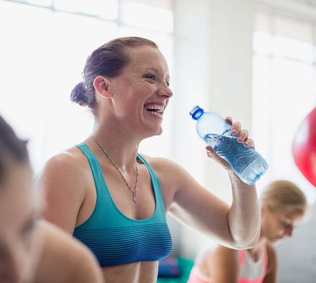 Woman drinking from water bottle during an exercise class