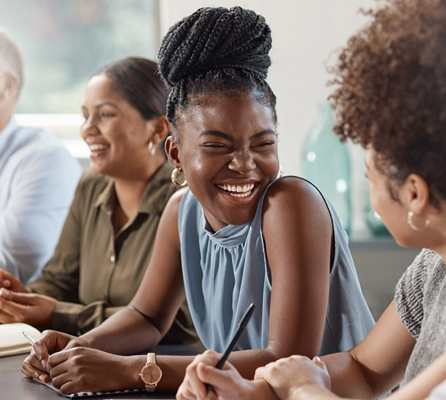 Woman sat with colleagues at a desk and laughing together
