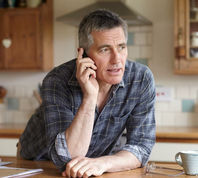 Man discussing his health subscription service on a phone call in his kitchen