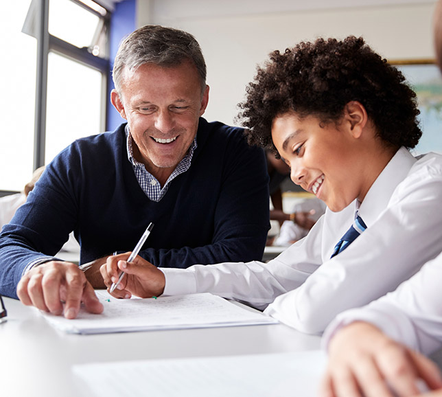 Teacher helping student who is writing in a notepad