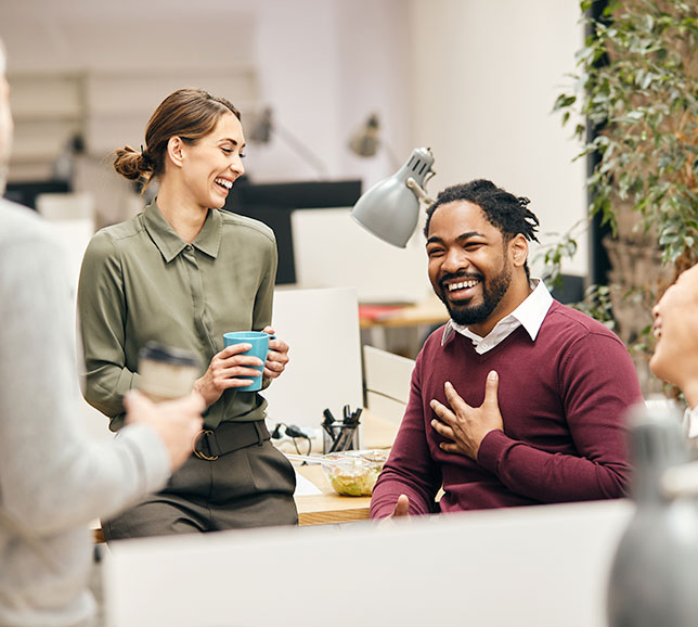 Office workers sat around their desks, laughing and smiling