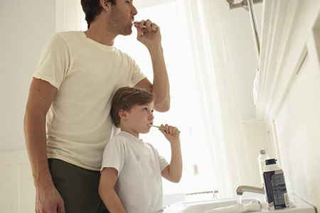 Father teaching son to clean his teeth