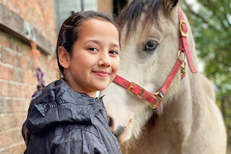 Young girl and horse with head collar