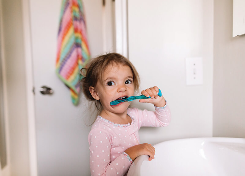 Toddler in pyjamas brushing her teeth