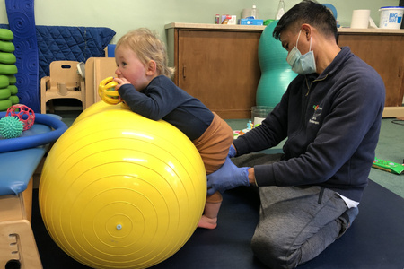 Physiotherapist with toddler on exercise ball