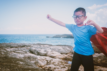 Child at beach wearing glasses and a cape