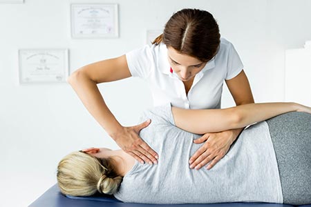 Chiropractor manipulating her patients back during an appointment