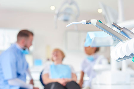 Close up of dental equipment with a dentist and nurse talking to patient 