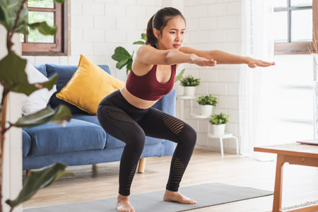 Woman squatting on yoga mat at home