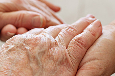 Person holding elderly person's hands