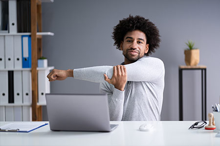 Man stretching arms at desk