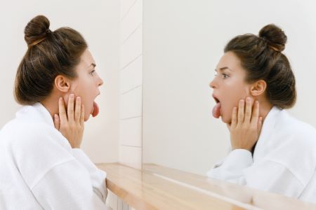 Woman checking her tongue in mirror