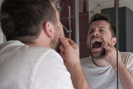 Man checking mouth in the bathroom mirror
