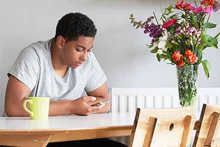 Man sat at kitchen table looking at mobile phione