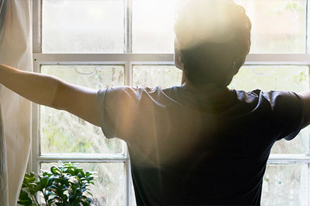 Man opening his curtains as he resets his habits