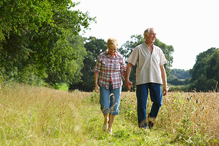 Older couple walking in summery field