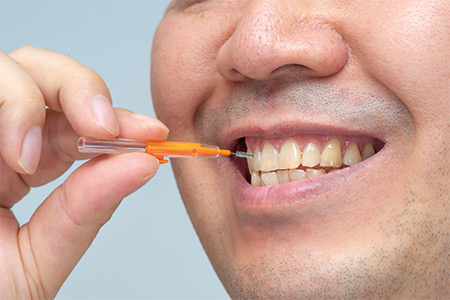 Person using interdental brush on front teeth