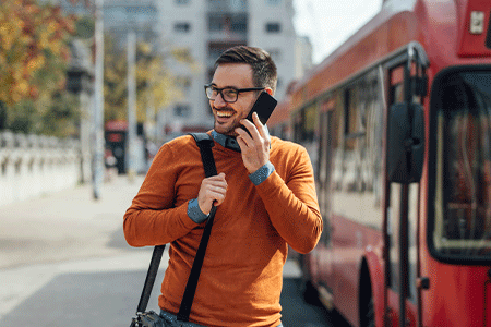 Man smiling and talking on his mobile phone at a bus stop