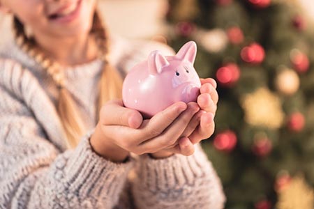 Woman holding piggy bank infront of christmas tree