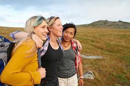 Woman with arms around two friends on a hike