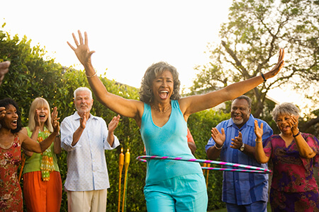 Older woman hula hooping with friends cheering