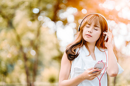 Woman wearing headphones under trees