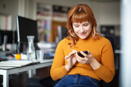 Woman using a smart phone at her desk