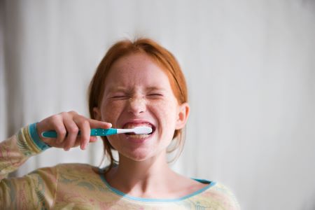 Girl brushing teeth with wide grin
