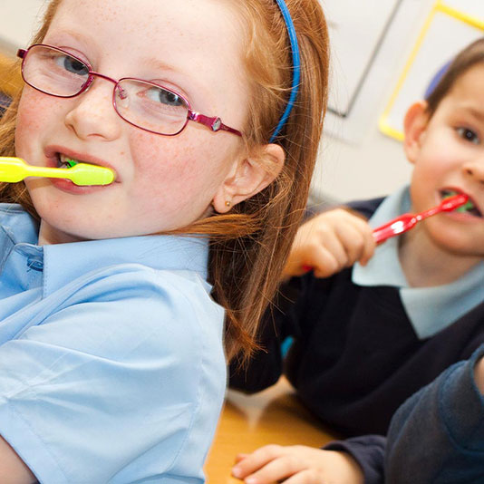 Children brushing teeth in classroom