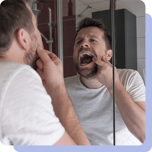 Man doing a mouth cancer check in the mirror at home