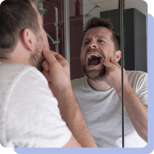 Man examining his mouth in the mirror