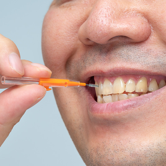 Man using interdental brush on front teeth