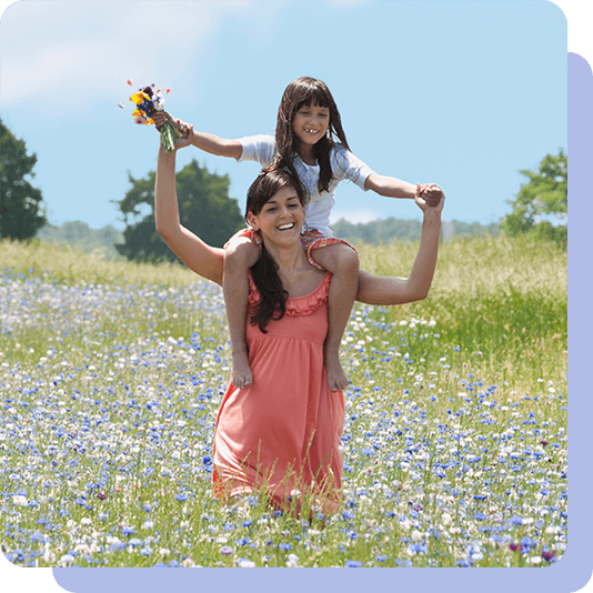 Daughter on mothers shoulders in a field of flowers