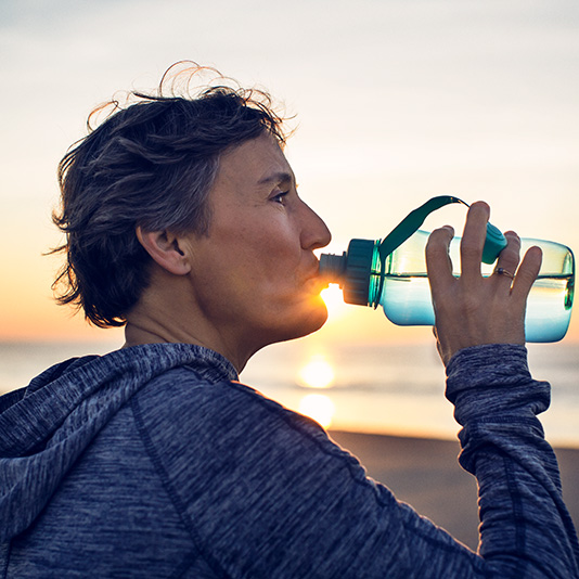 Woman drinking from water bottle on the beach