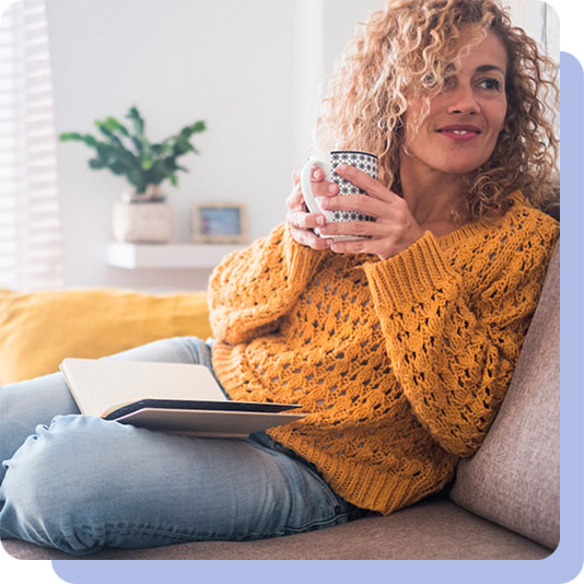 Woman sat on sofa drinking from mug