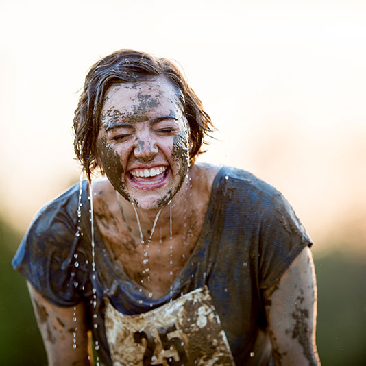 Woman smiling whilst covered in mud for charity race