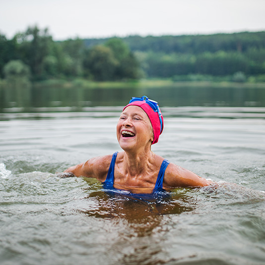 Woman smiling whilst swimming in a lake