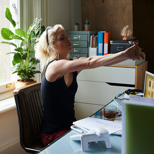 Woman stretching her arms whilst sat at desk