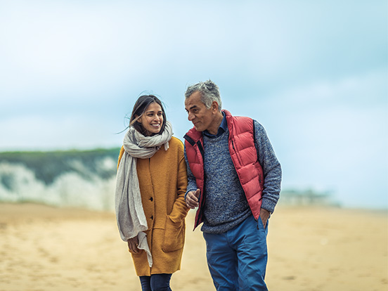 Man and woman walking along sandy beach in the winter