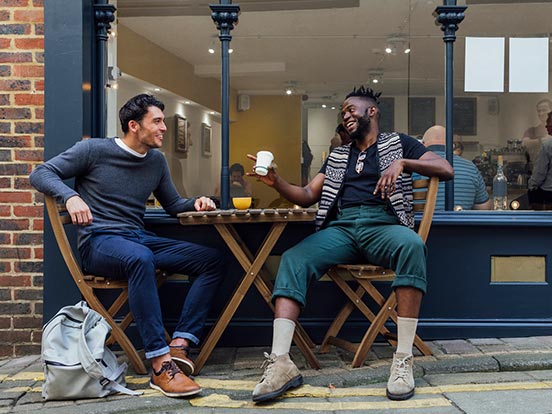 Two men sat outside coffee shop and talking