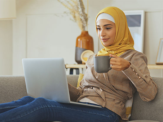 Lady browsing health plans on laptop with cup of tea