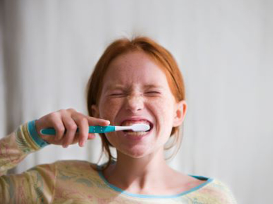 Girl grinning whilst brushing her teeth