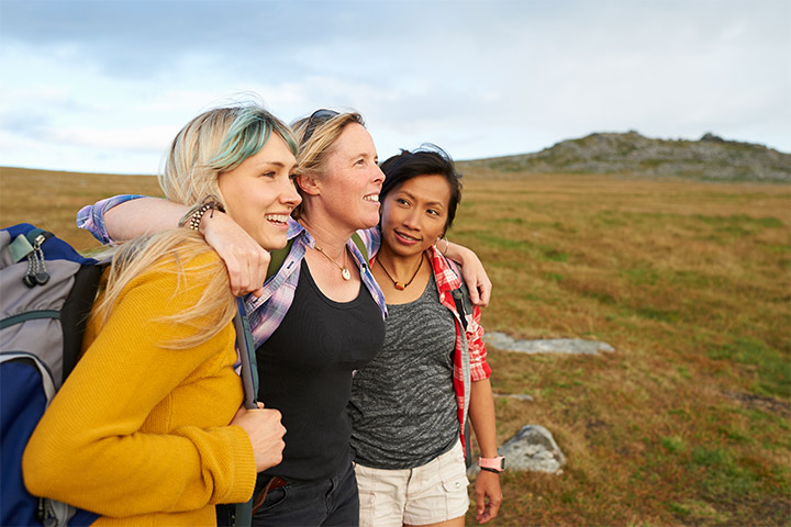 Woman with arms around two friends on a hike